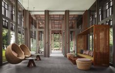 the inside of a house with large windows and wicker furniture on either side of the room