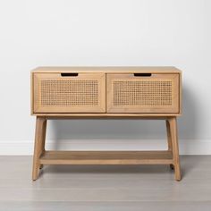 a wooden table with two drawers on it and a white wall in the back ground