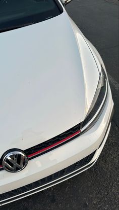 the front end of a white car parked in a parking lot