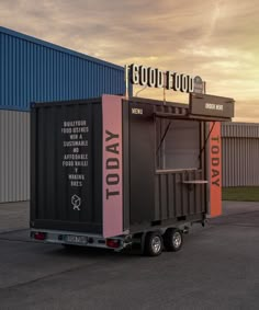 a truck with a trailer attached to it parked in front of a building that says good food