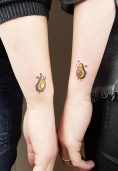 two people holding hands with tattoos on their arms and one has an avocado