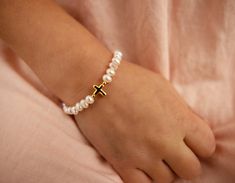 This personalized keepsake bracelet is made with beautiful soft white freshwater pearls and 14K gold (over sterling silver). This includes a gold-plated heart charm that includes FREE engraving up to 9 characters. Gorgeous strand of pearls accented with a 14K gold-plated dainty cross. Bracelet is hand-beaded in the USA on strong gold stainless steel wire with durable lobster clasp. This makes a very special gift for baptism, christening, first communion, or other religious gift. A timeless class Baptism Bracelet, Pink Gift Box, Baby Pearls, Kids Bracelets, White Freshwater Pearl, Cross Bracelet, Pink Gifts, Gold Cross, Cross Charms