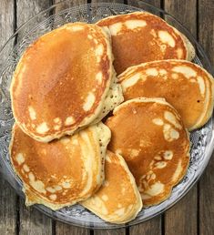 pancakes on a glass plate sitting on top of a wooden table