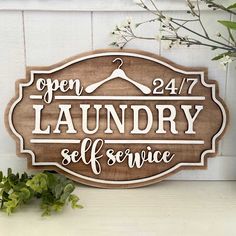 a wooden sign that says open laundry self service on the side of a white wall