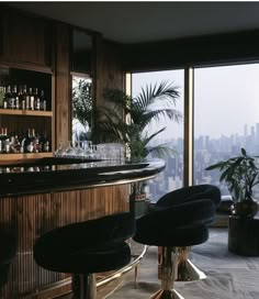 a bar with stools and bottles in front of a window overlooking a cityscape