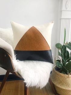 a white and black pillow sitting on top of a wooden chair next to a potted plant