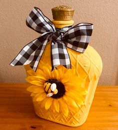 a yellow bottle with a black and white bow on it sitting on a wooden table