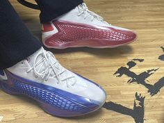 a person standing on top of a wooden floor next to a pair of basketball shoes