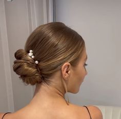 a woman with her hair in a low bun and pearls on the back of her head