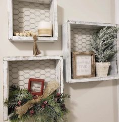 two white shelves decorated with christmas decorations and greenery, one is hanging on the wall