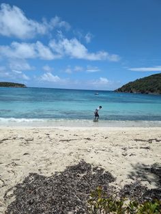 a man standing on top of a sandy beach next to the ocean