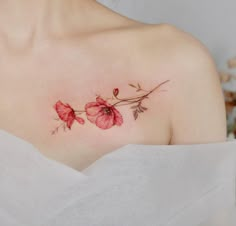 a close up of a woman's chest with red flowers on her left shoulder