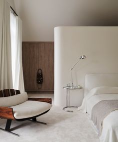 a bedroom with a white bed, chair and lamp in it's center area