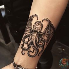 an octopus tattoo on the arm and wrist is shown in black ink with chains around it