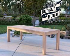 a wooden bench sitting on top of a cement floor next to a lush green park