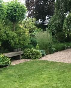 a wooden bench sitting in the middle of a lush green park