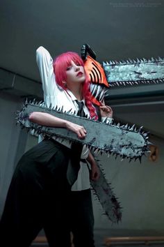 a woman with red hair holding a chainsaw