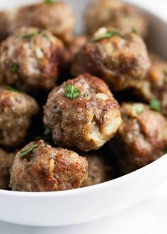 a white bowl filled with meatballs covered in parsley