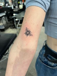 a woman's arm with a small tattoo of a bee on the back of her arm