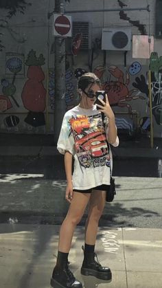 a woman taking a selfie in front of a graffiti covered wall with her cell phone