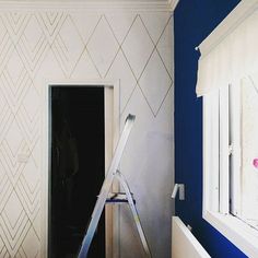 a ladder is leaning against the wall in front of an open door with white paint on it