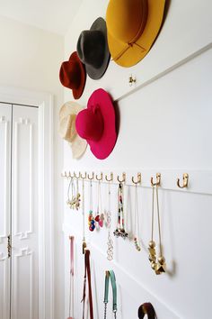 several hats are hanging on the wall with necklaces attached to it and other accessories