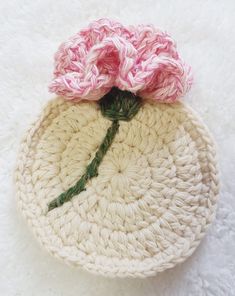 a crocheted flower sits on top of a white knitted basket with pink flowers