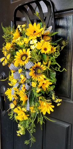 a sunflower wreath hangs on the front door of a house with black and white checkered ribbon