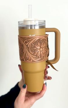 a woman holding up a coffee cup with a handle and flower design on the side