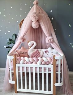 a baby crib with pink and white decorations on the walls, including a swan bed