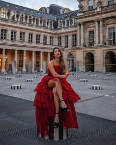 a woman in a red dress sitting on top of a pole