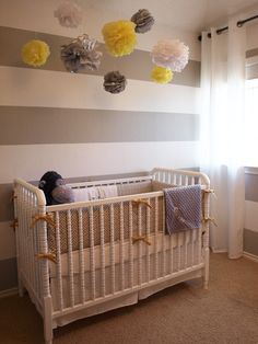 a baby crib in a room with striped walls and paper flowers hanging from the ceiling