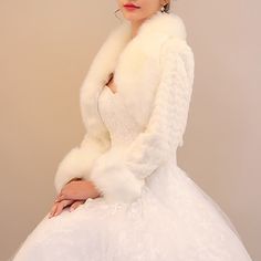 a woman in a white dress and fur coat posing for the camera with her hands on her hips