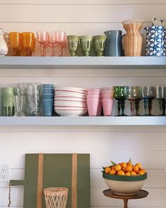 the shelves are filled with bowls, cups, and vases in different colors on them