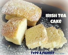 three pieces of cake sitting on top of a black plate with sugar sprinkled around it