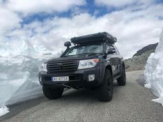 a vehicle parked on the side of a road near snow covered mountains and icebergs