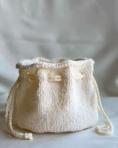 a white knitted bag sitting on top of a bed