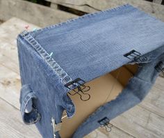 an old pair of blue jeans is sitting on a wooden table with scissors in it