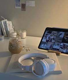 an open book with headphones on top of it next to a tablet and some books