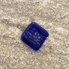 a blue square object sitting on top of a sandy ground