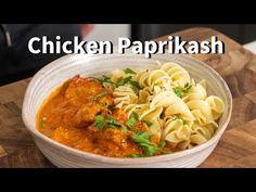 a bowl filled with pasta and chicken parmesan on top of a wooden cutting board