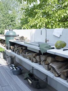 an outdoor kitchen with lots of wood stacked on top of it