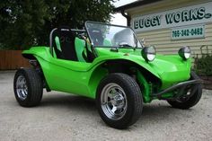 a green dune buggy parked in front of a building