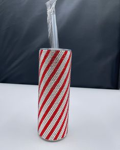 a red and white striped glass with a straw sticking out of it's side