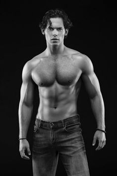 a shirtless man with no shirt on posing for a black and white photo in jeans