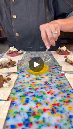 a person is making food on a table with colored paper and water in the bowl