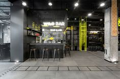 the inside of a building that has yellow and black accents on it, with bar stools