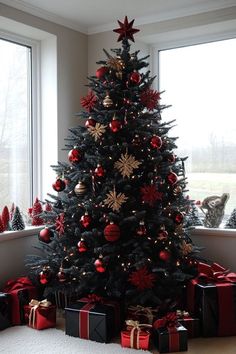 a christmas tree with presents under it in front of a large window, decorated with red and gold ornaments