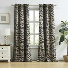 a zebra print curtain hanging in front of a window with a potted plant next to it