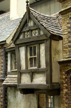 a doll house made out of wood and stone with a window on the top floor